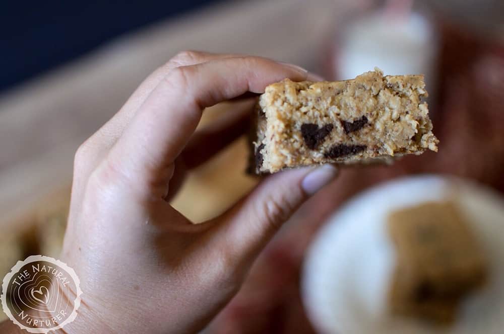 Holding one of the chickpea blondies with a left hand above the table.