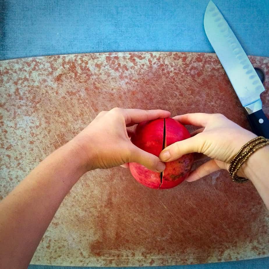 Using two hands to break the pomegranate in two halves