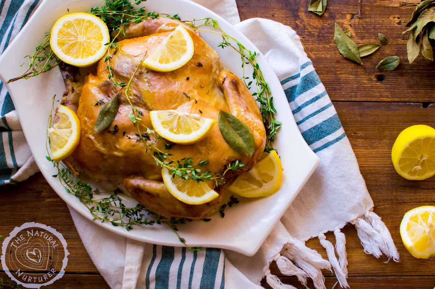 Closeup of the delicious slow cooker lemon thyme whole chicken decorated with lemons on a big white tray