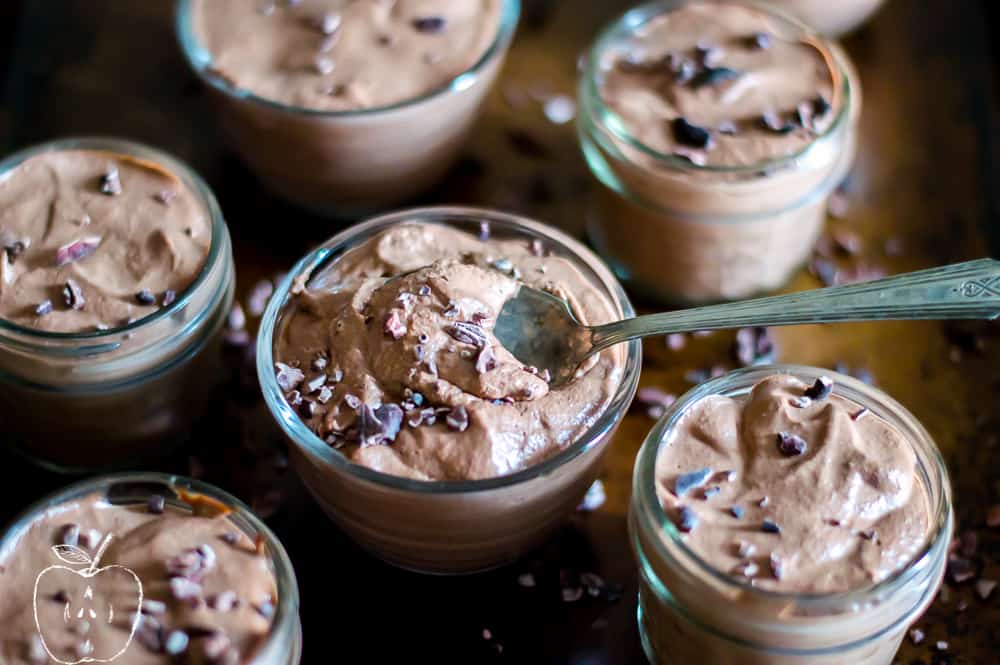 Instant Chocolate Chia Pudding looking super inviting with one spoon dipped inside the central jar covered with chocolate chunks