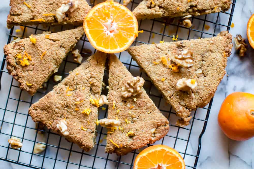 Six Paleo Orange Walnut Scones served in the morning with a few oranges on a rack