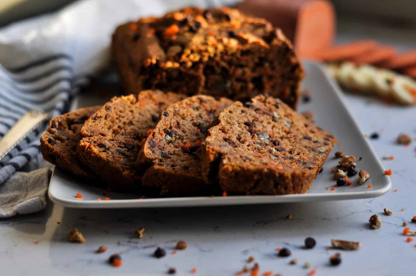 Chocolate chip carrot bread looking extra inviting and healthy with veggies blurred in the background.