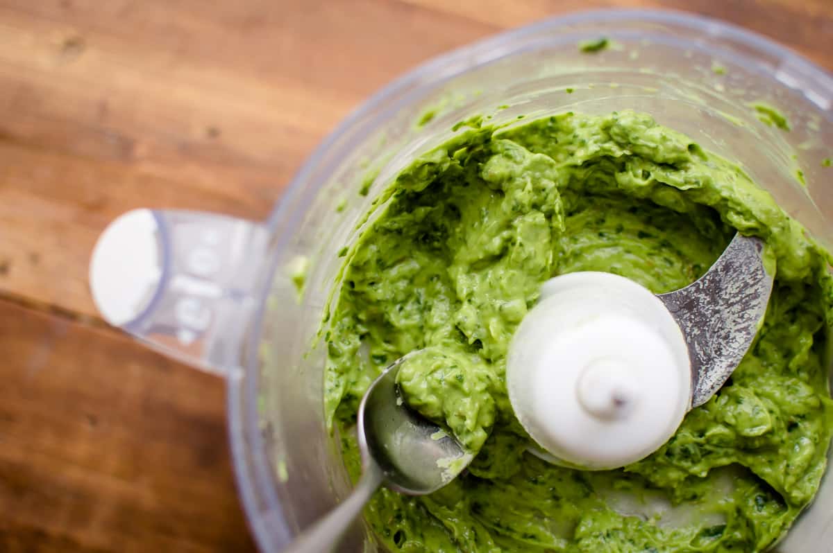 Overhead on a big blender with plenty of healthy guacamole and a small metal spoon inside