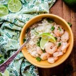 Overhead on a bowl full of the delicious Zesty Lime Shrimp with Simple Cauliflower Rice and pieces of lime on the wooden table