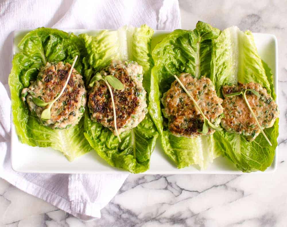 veggie-loaded chicken burgers on a platter with lettuce