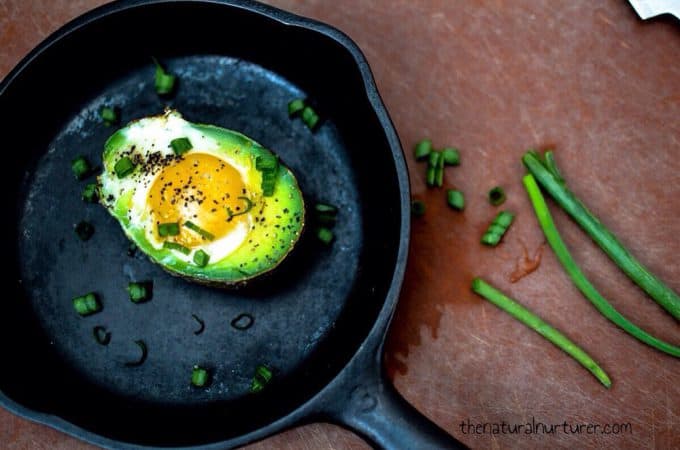 Baked Egg in an Avocado served in a small skillet with green onions on the side