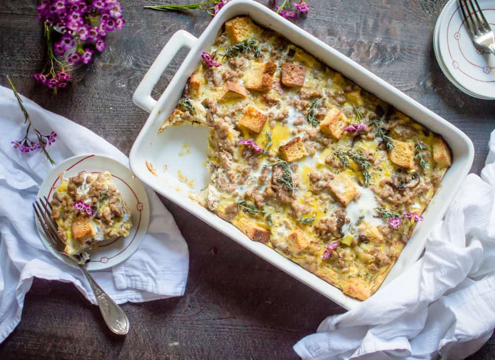 Sausage Leek & Mushroom Breakfast Casserole ready in a big tray and served in a small white plate with a fork on the top