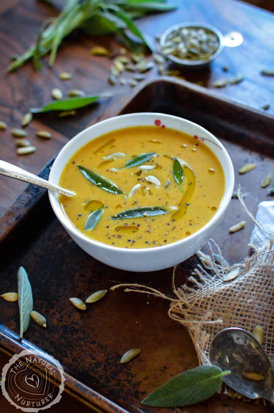 Savory Pumpkin Soup served on a big tray with fresh herbs around the bowl