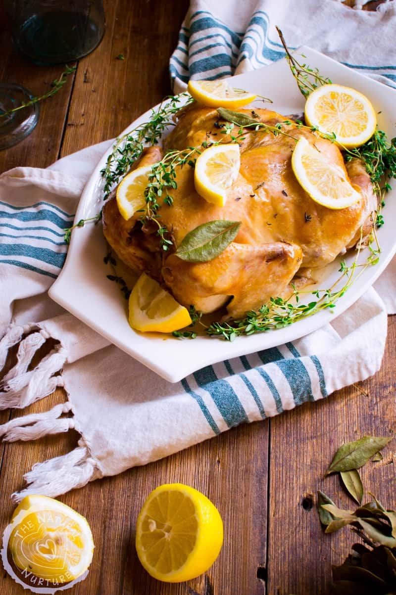 Slow Cooker Lemon Thyme Whole Chicken beautifully served with herbs and lemon on the side