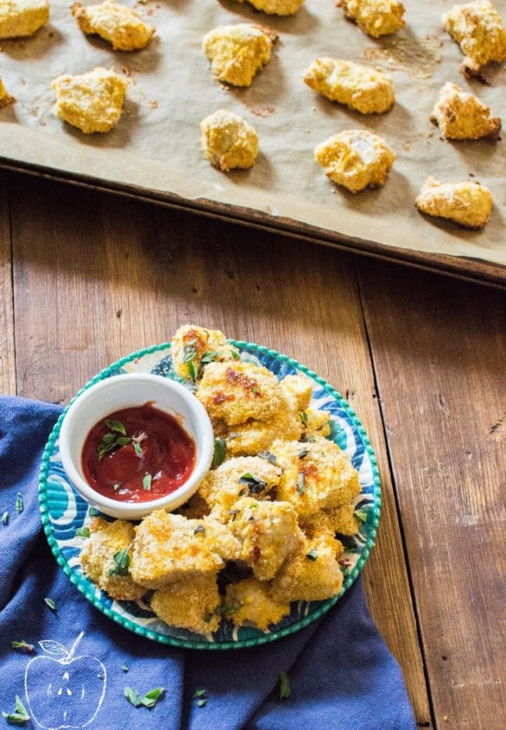 Grain-Free Oven Baked Chicken Nuggets served with sauce with even more nuggets right next to the plate in a tray