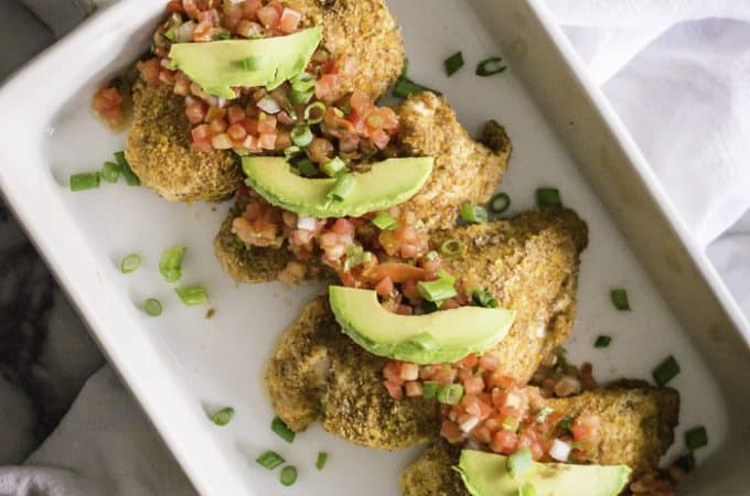 Overhead on the delicious healthy baked salsa chicken in a big white tray with avocado halves around it