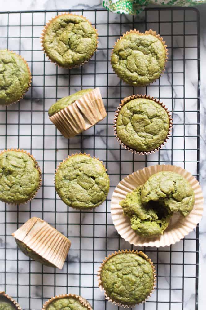 Oatmeal green smoothie muffins line up on a cooling rack on a white marble table top