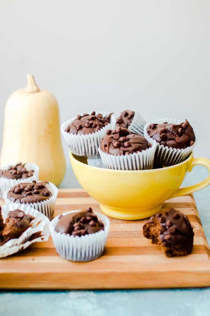 Nut-Free Paleo Chocolate Butternut Squash Muffins served in a yellow bowl with a big squash in the back.