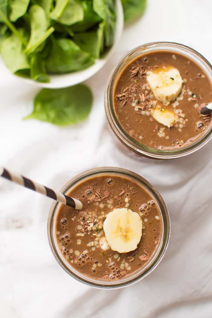 Overhead on two jars full of healthy and delicious chocolate banana smoothie each, with straws and slices of banana on top