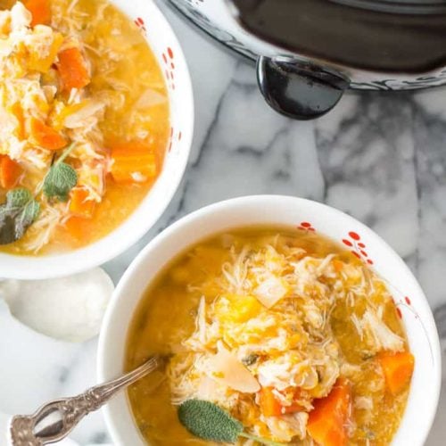 Slow Cooker Chicken Butternut Squash Stew ready and served in two big white bowls next to the pan with more delicious soup inside