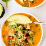 Overhead on a big bowl of the delicious Mexican Slow Cooker Chicken Stew with avocado, greens and other healthy ingredients on top