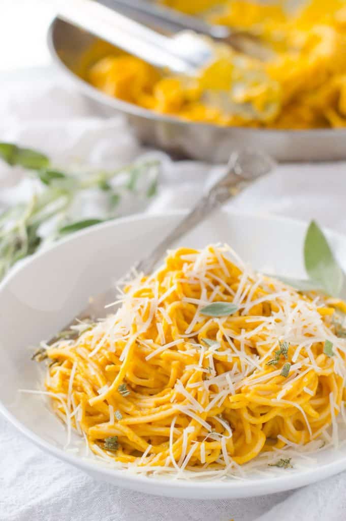 Bowl of pumpkin pasta sauce and noodles with parm cheese and sage on top