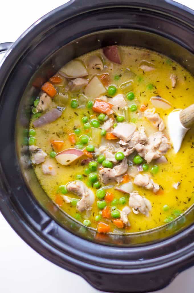 Overhead on the delicious Slow Cooker Creamy Vegetable Chicken Stew with a wooden ladle inside