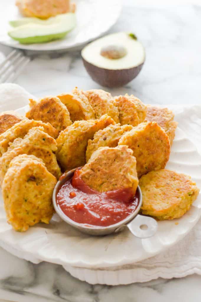 Chickpea veggie nuggets on a plate with ketchup and one nugget dunked in the dip.