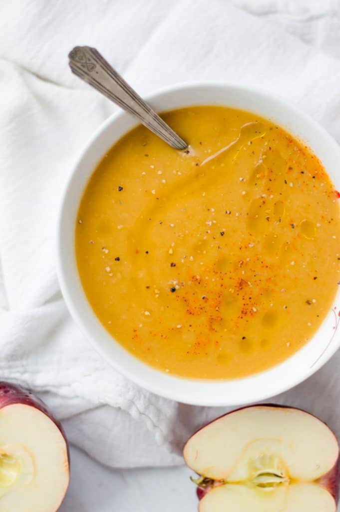 A bowl of Instant Pot butternut squash soup with apples next to the bowl