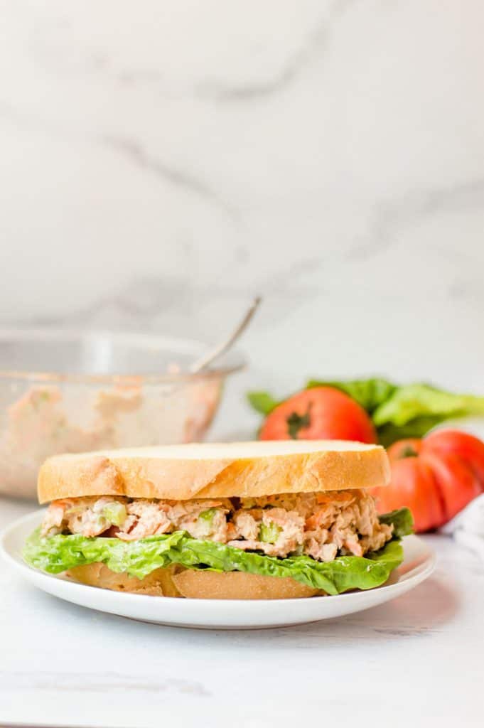 Healthy Tuna salad on a sandwich with lettuce and sandwich ingredients in the background. 