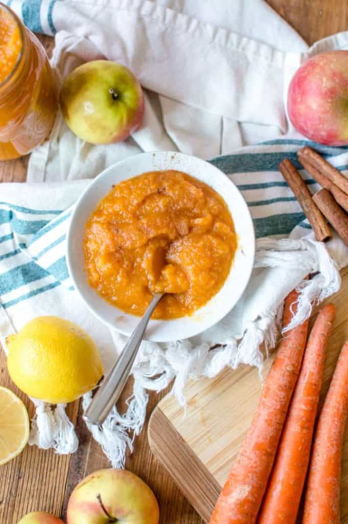 A bowl of veggie-loaded homemade applesauce with ingredient around it. 