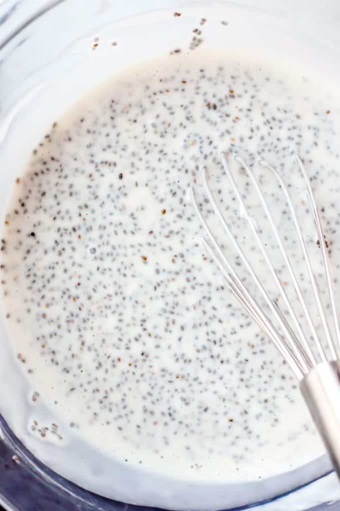 Coconut chia pudding in a bowl with a whisk after being mixed together. 