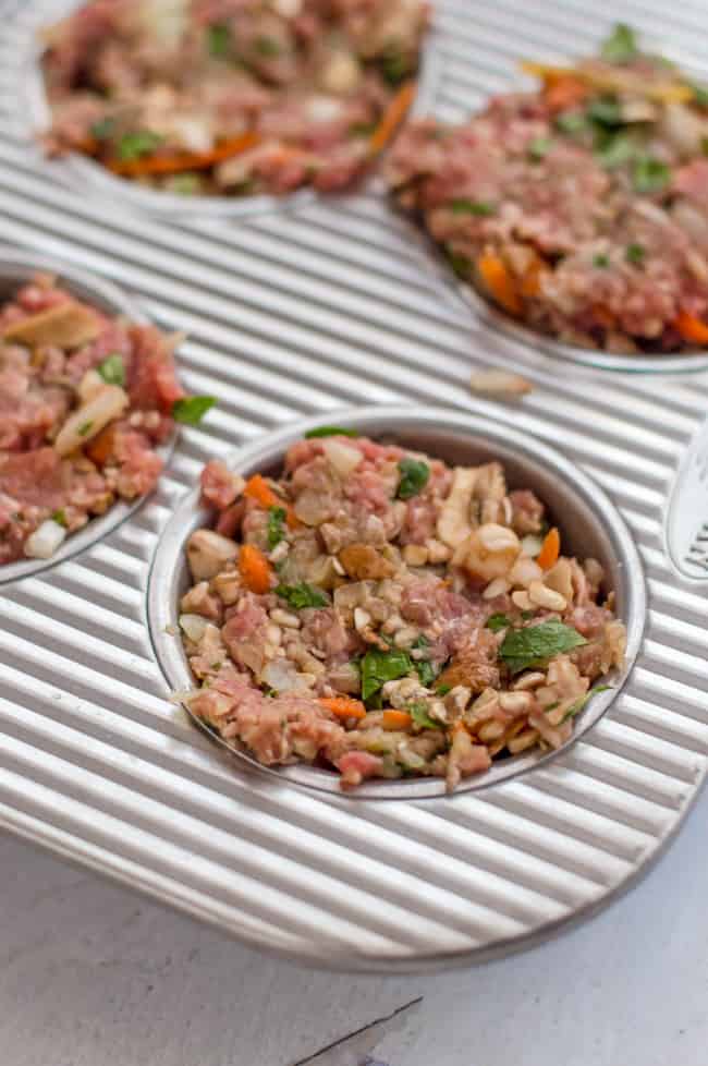Veggie-loaded mini meatloaves portioned out in a muffin tin before baking. 