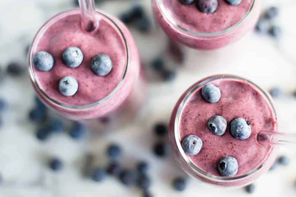 A cauliflower blueberry smoothie in glasses topped with fresh berries.