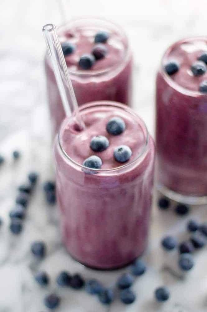 A cauliflower blueberry smoothie in glasses topped with fresh berries.