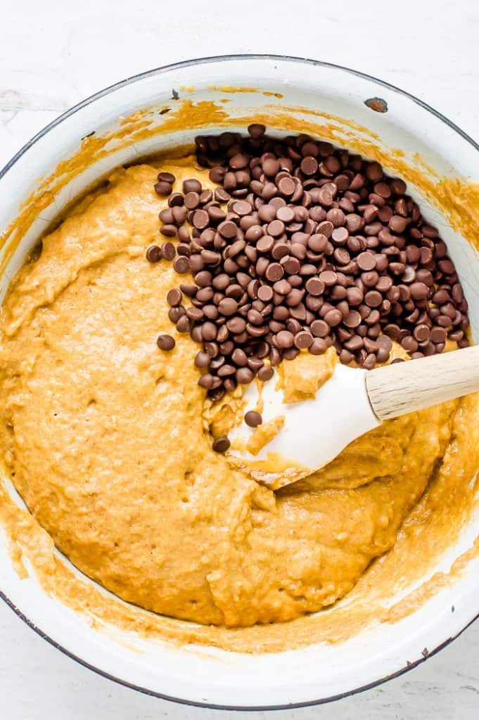 The batter for sweet potato banana bread in a bowl with a spoon and chocolate chips.