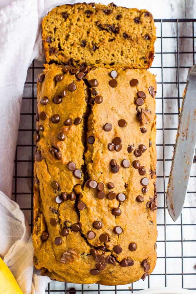 Sweet potato banana bread on a cooling rack with a slice cut from it. 
