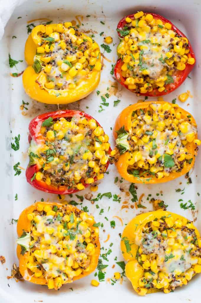 A tray of corn quinoa stuffed peppers in their baking dish with cilantro sprinkled over them.