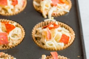 Pizza muffins in a muffin tin before being baked.