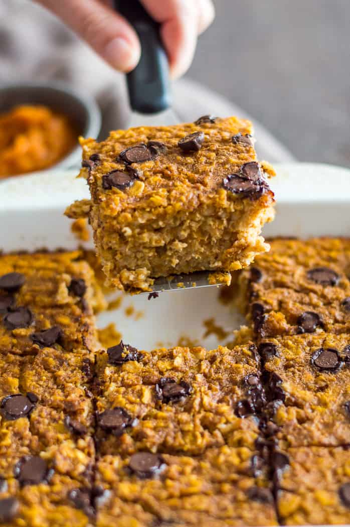 A slice of baked pumpkin oatmeal being lifted out of the tray with a spatula.