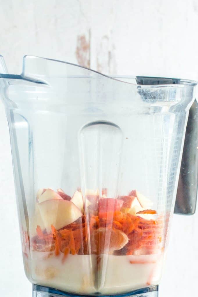 Ingredients for apple carrot smoothie in a blender before blending.