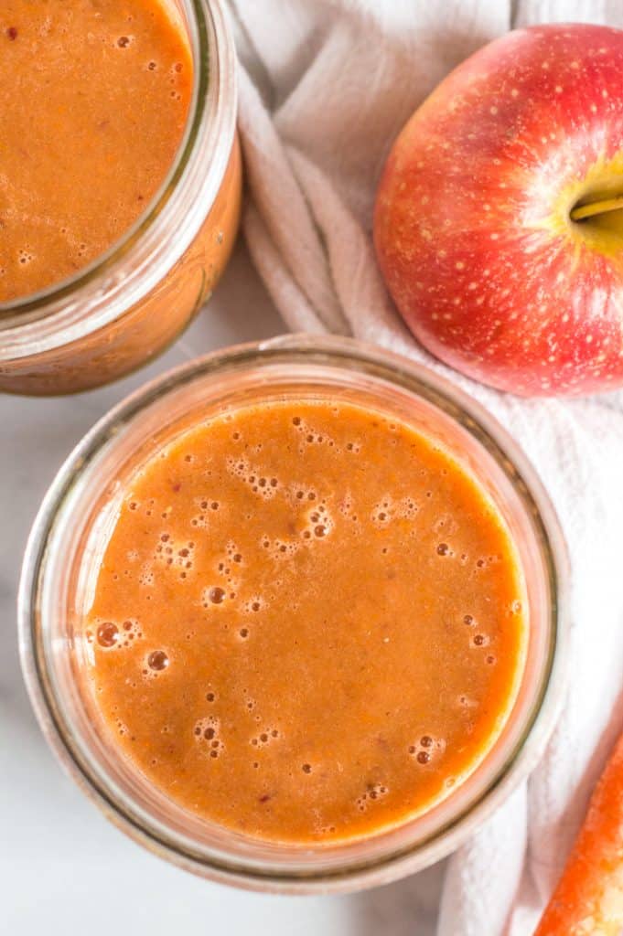 Apple carrot smoothie in two mason jars on a table.