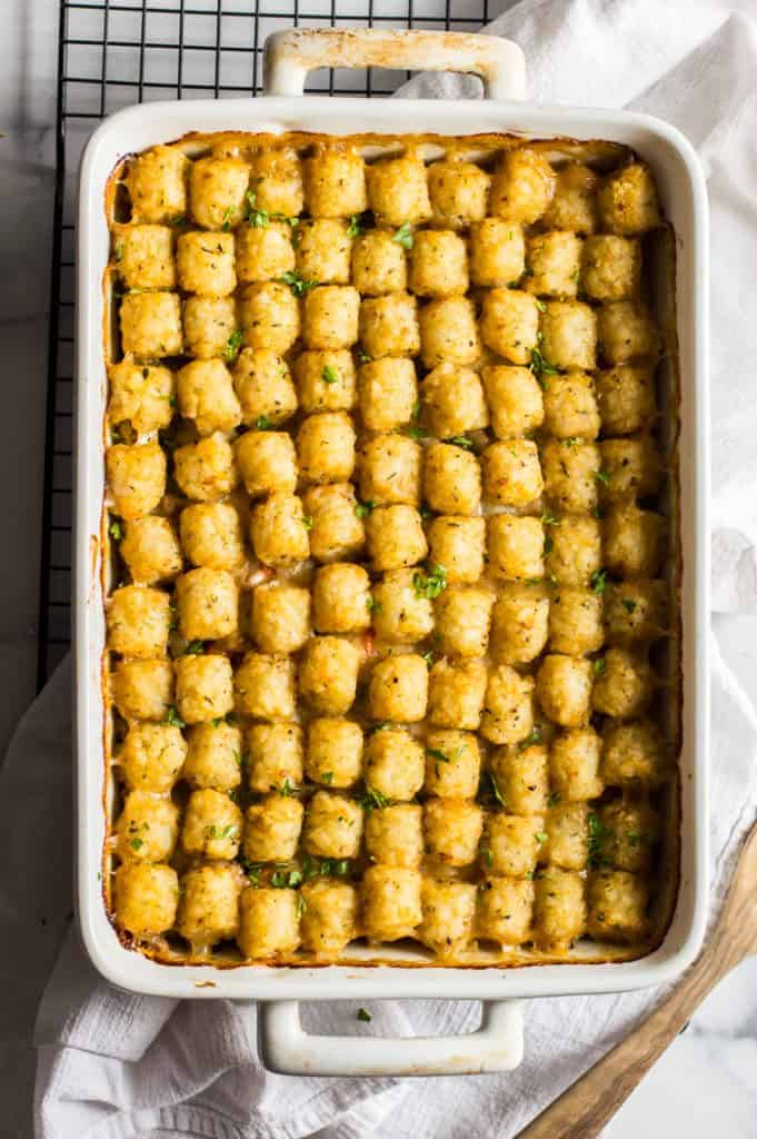 Veggie-loaded tater tot casserole after baking on a cooling rack with a white napkin.