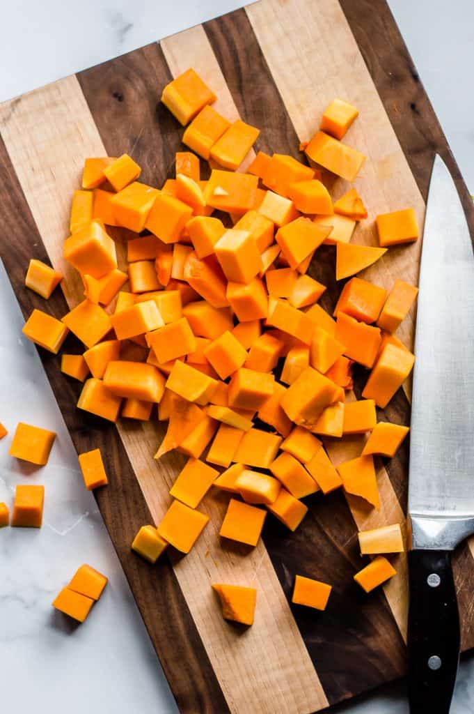 Cubed butternut squash on a cutting board with a knife. 