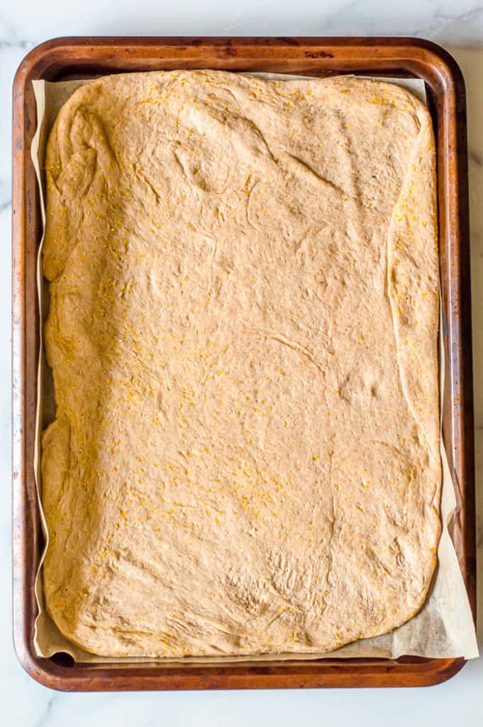 Pizza down in a rectangle baking pan with parchment paper.