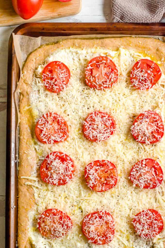 Fresh tomato slices on a pizza crust covered in cheese.