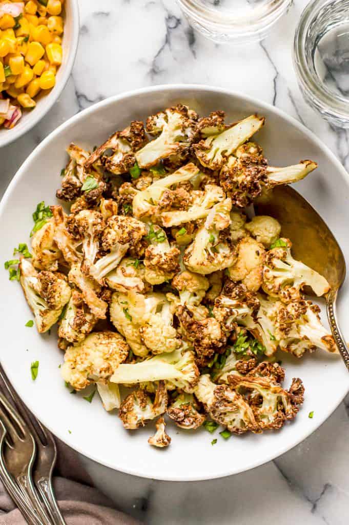 Air fryer cauliflower in a bowl on a table with a metal spoon.