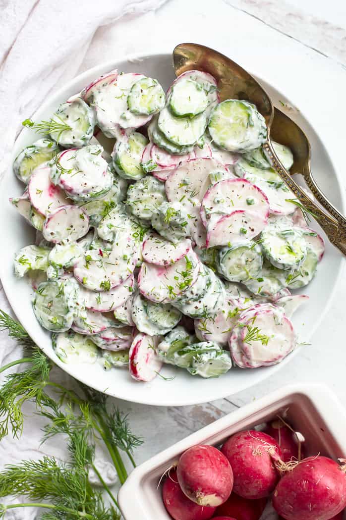 Creamy cucumber radish salad in a bowl with two spoons.