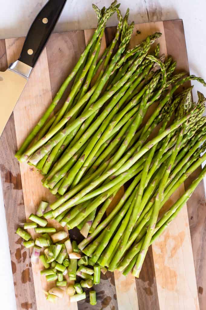 Fresh asparagus on a wooden cutting board with the bottom ends trimmed off.
