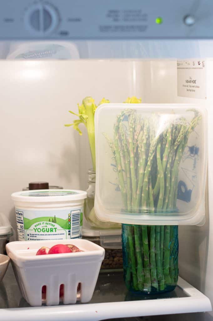 Asparagus in a jar with a bag over the top in the fridge.