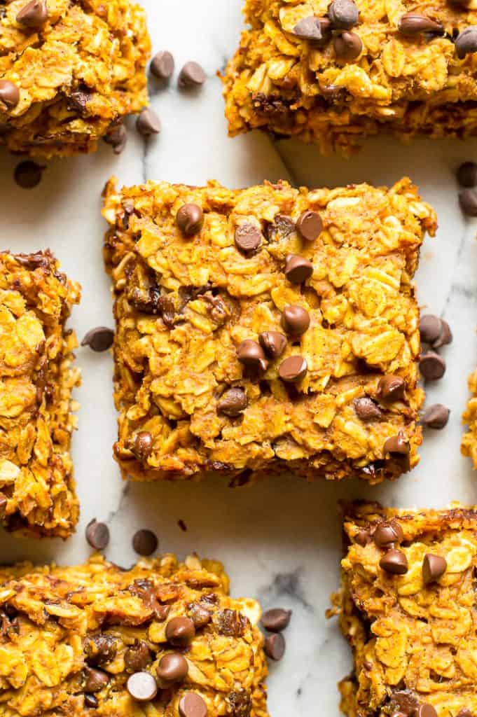 Peanut Butter Pumpkin Oatmeal Bars on a white marble table with chocolate chips scattered around.
