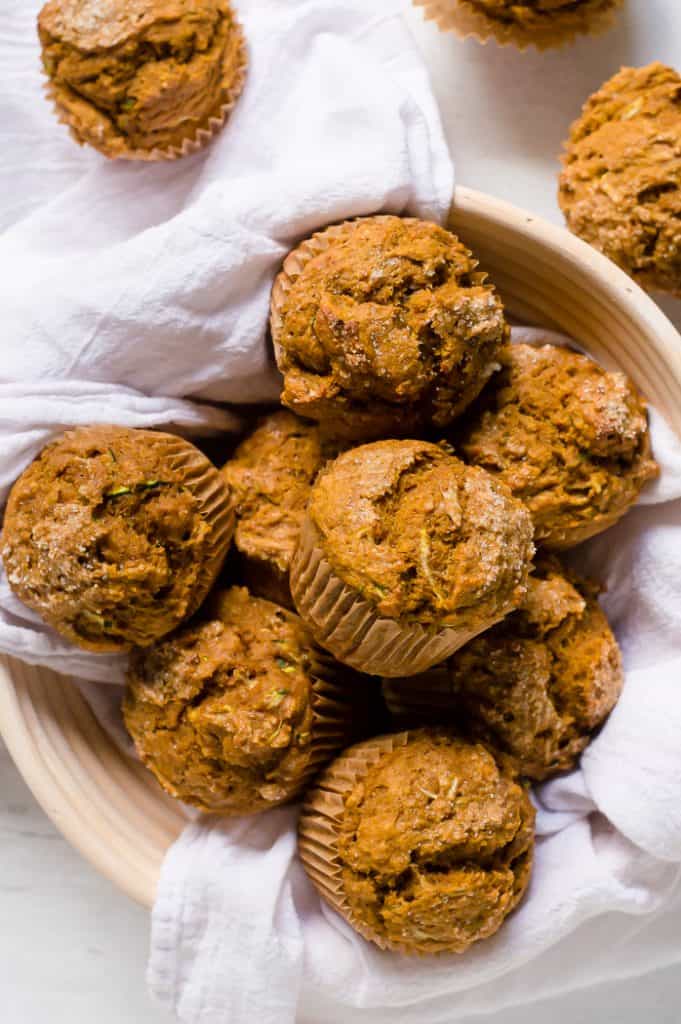 Pumpkin Zucchini muffins in a basket with a white napkin on a white table.
