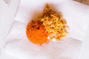 Grated carrots and apples in the middle of a paper towel.