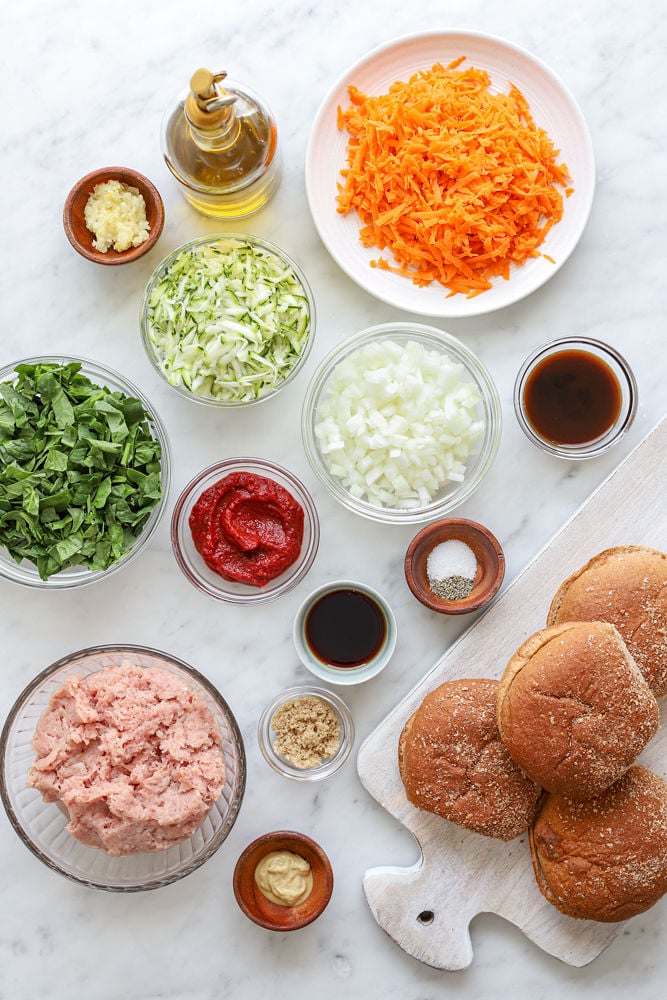 Ingredients for veggie-loaded turkey sloppy joes spread out on a white marble table in bowls.
