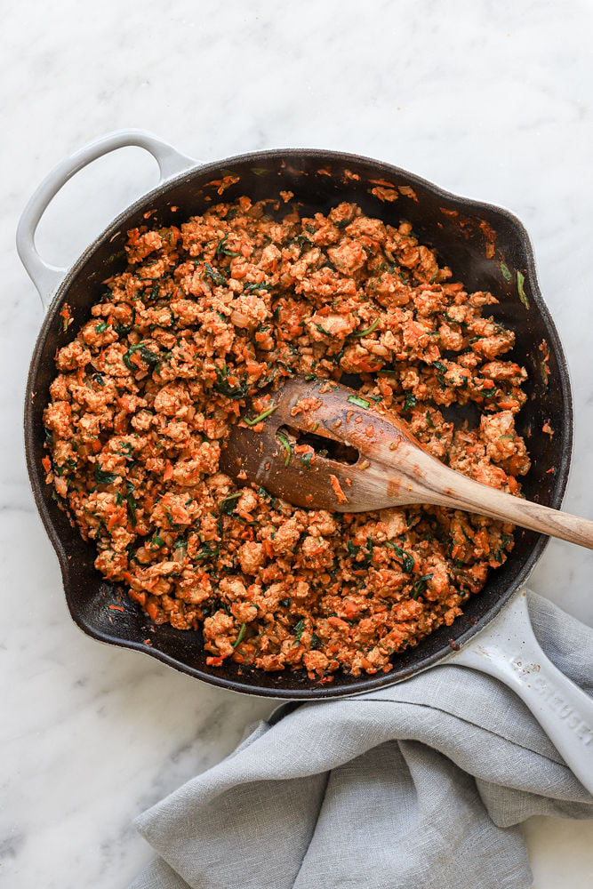 Veggie-Loaded turkey sloppy joe mixture in a skillet with a wooden spoon after being cooked. 